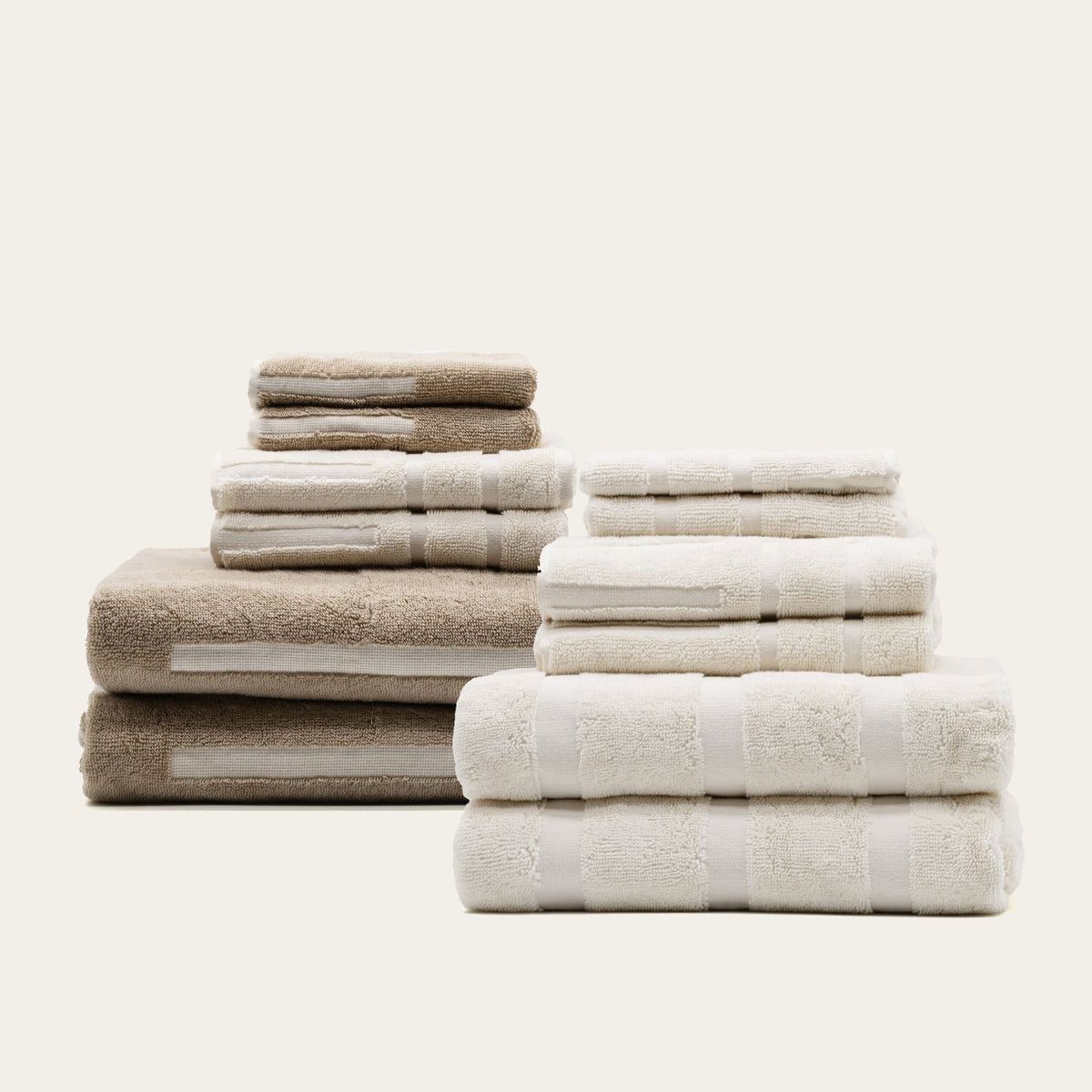 Assorted cotton towels in beige and off-white, stacked with textured dobby bands