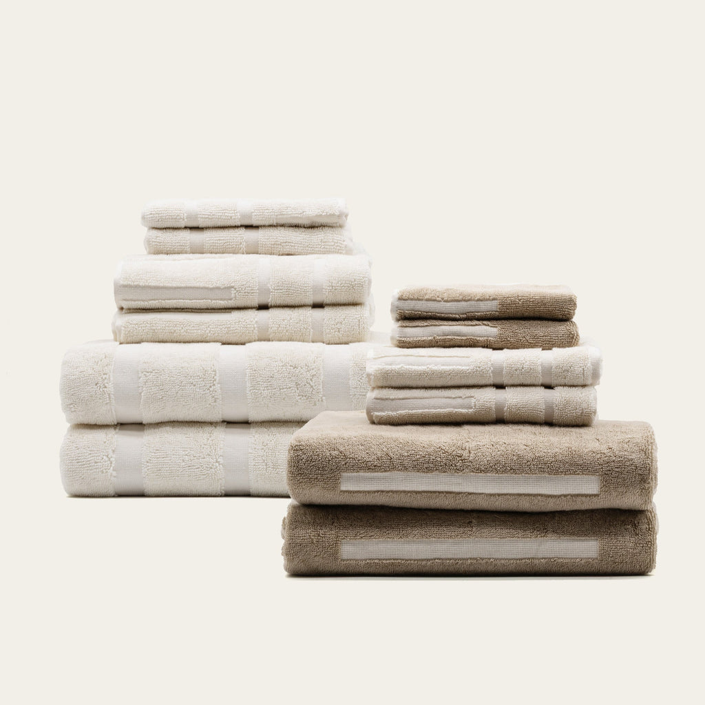 Stacked ecru and tan cotton towels with textured loops and stitched stripes.