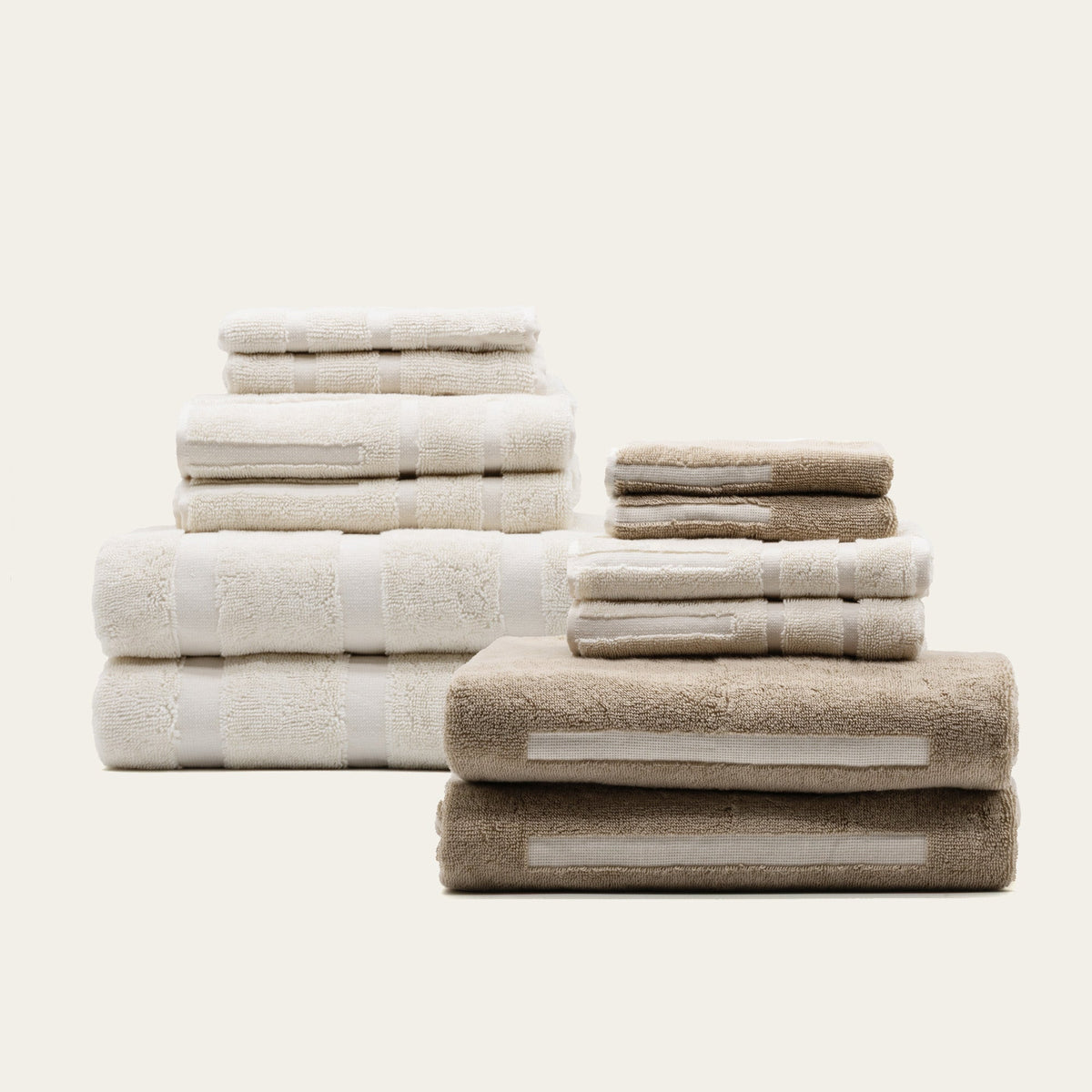 Stacked ecru and tan cotton towels with textured loops and stitched stripes.