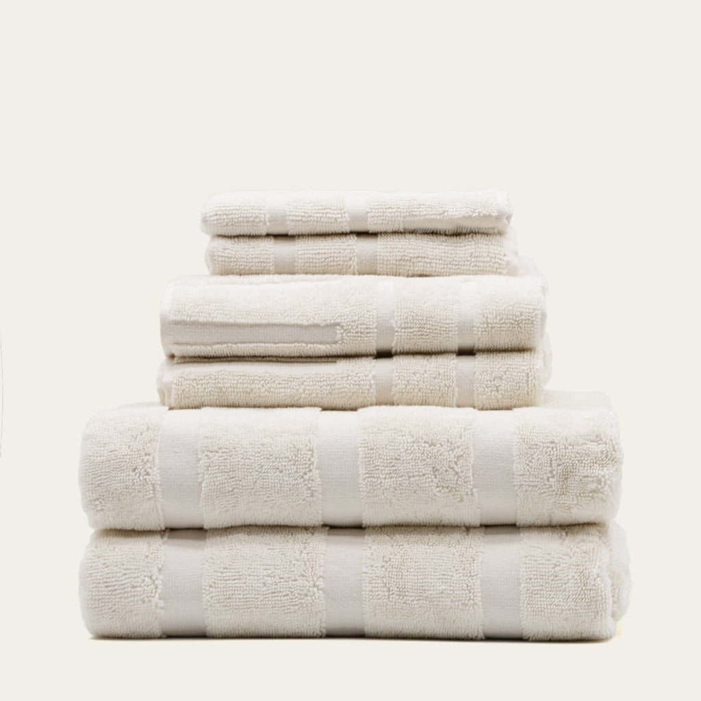 Stack of off-white cotton towels with visible dobby bands and plush terry texture
