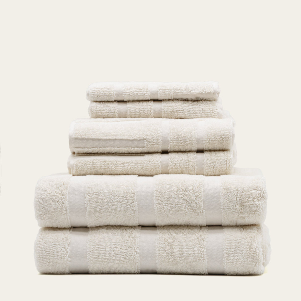 Stack of ecru cotton bath towels with jacquard pattern, neatly folded