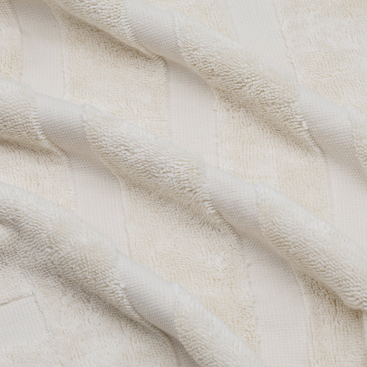 Off-white cotton towel with textured dobby pattern and soft terry loops