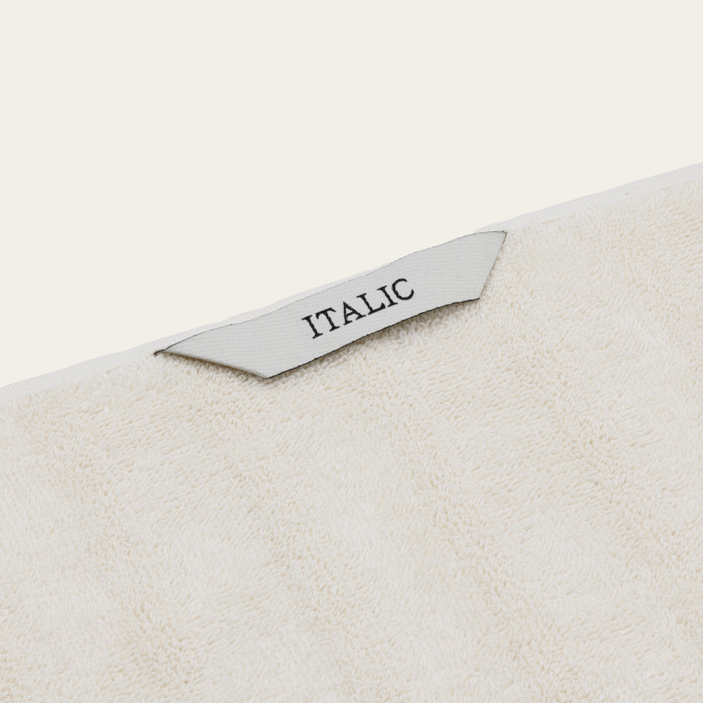 Ecru cotton towel corner with decorative woven border and stitched label