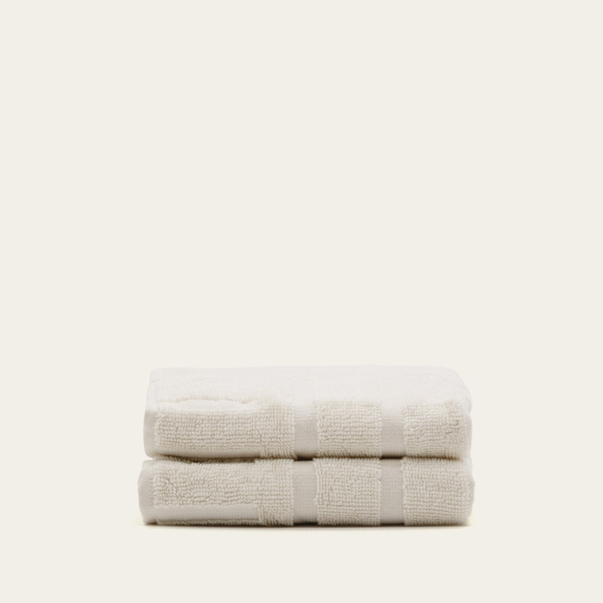 Ecru cotton hand towels, neatly folded with banded trim