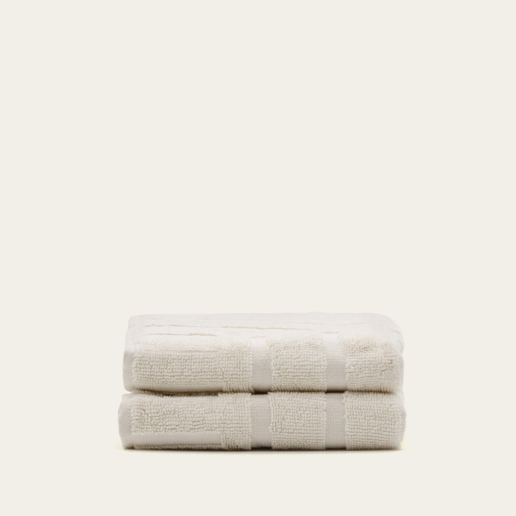 Two-fold light beige cotton bath towels with stitched border stripe bands