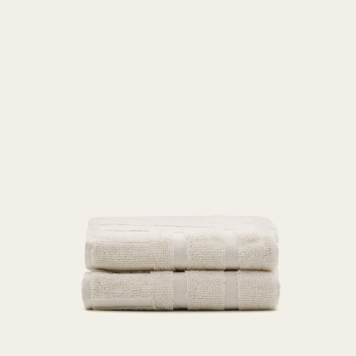 Two-fold light beige cotton bath towels with stitched border stripe bands