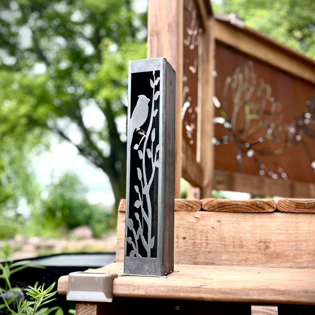 Steel solar luminary pillar panel with cardinal silhouette, mounted on outdoor post