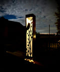 Steel solar garden luminary pillar with cardinal cutout, illuminated at night
