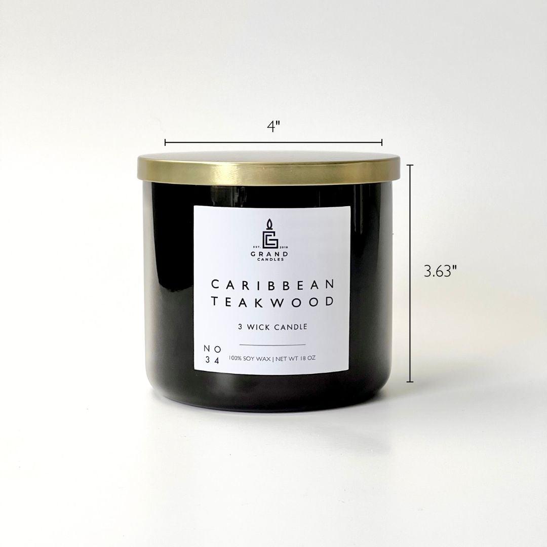 Caribbean teakwood soy candle black glass jar with white label and gold lid.