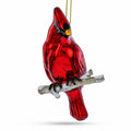 Red cardinal blown glass ornament with branch base and gold hanging cord.