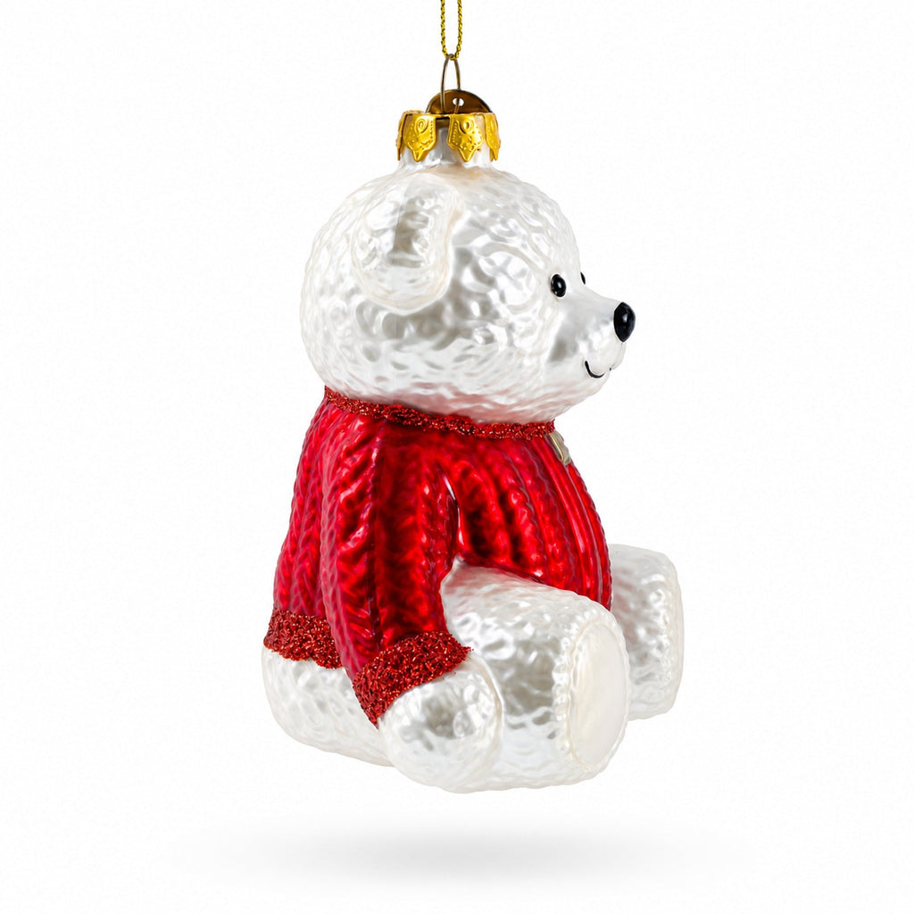 White teddy bear glass ornament in a red sweater, close-up with gold hanging top