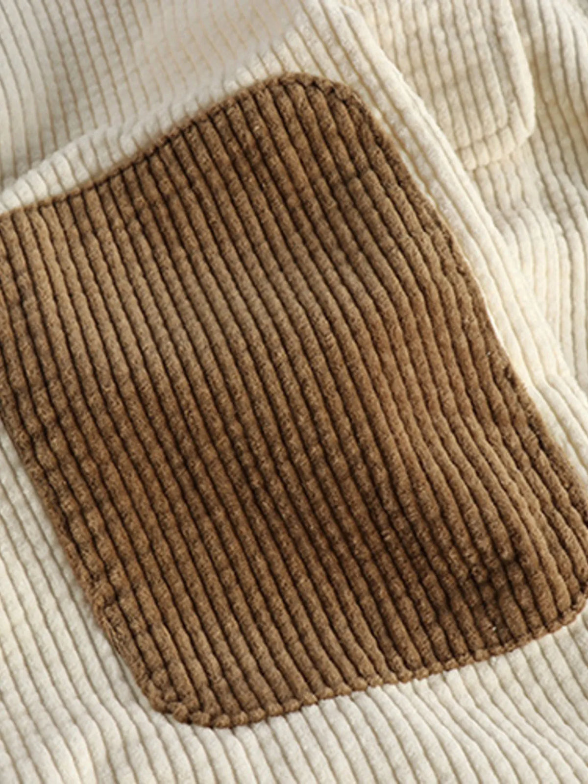 Close-up of brown corduroy pocket patch on a light beige button-up shirt