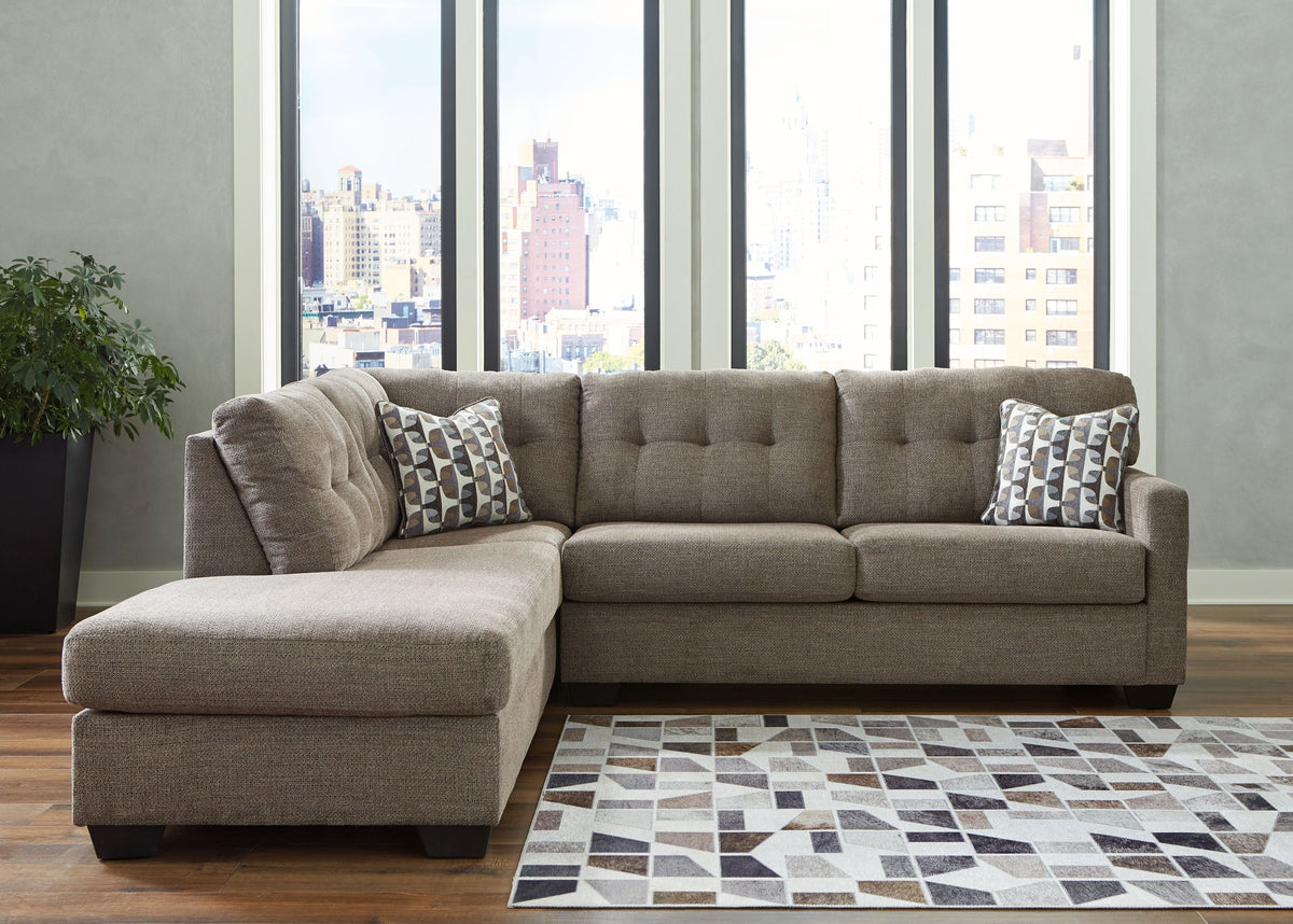 Light gray corner chaise sectional with chaise arm and two patterned pillows