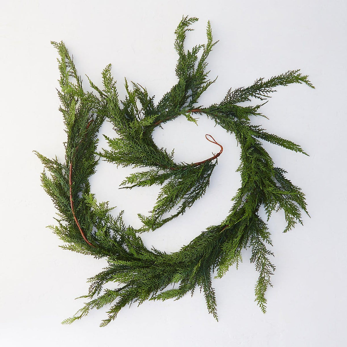 Looped faux cedar garland with dense green needle-like foliage