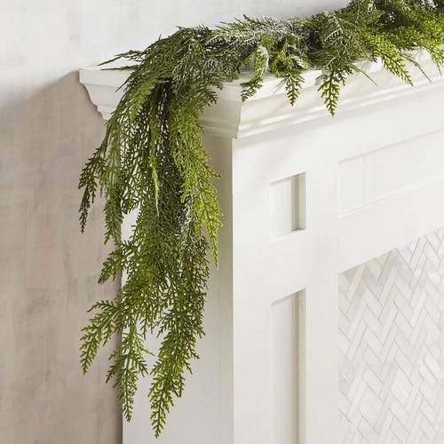 Hanging faux cedar garland draped along a doorway with green needle branches