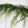 Faux cedar garland with dense green needle-like branches on brown stems