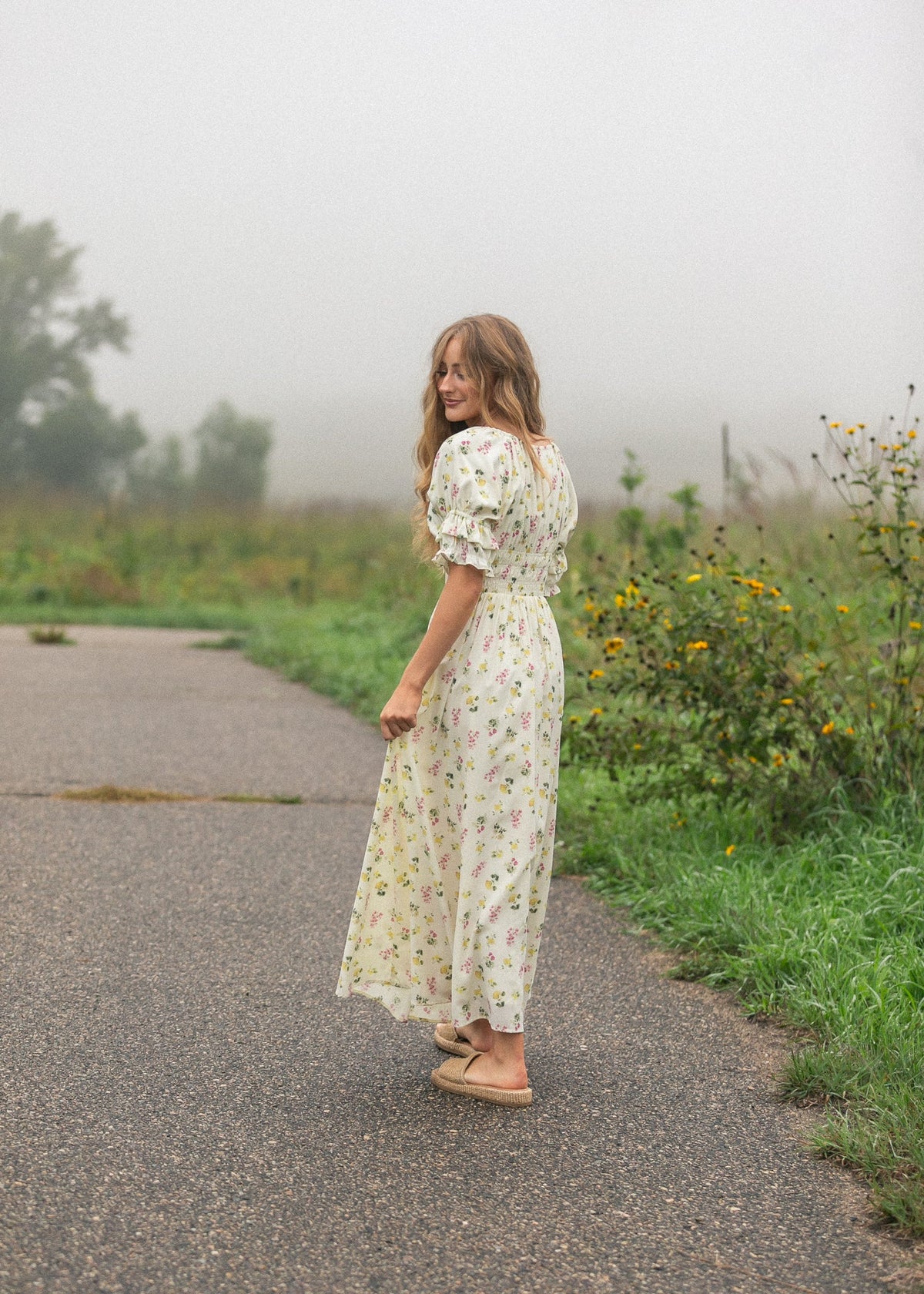 Back view of cream floral maxi dress with puff sleeves and gathered waist ruffles.