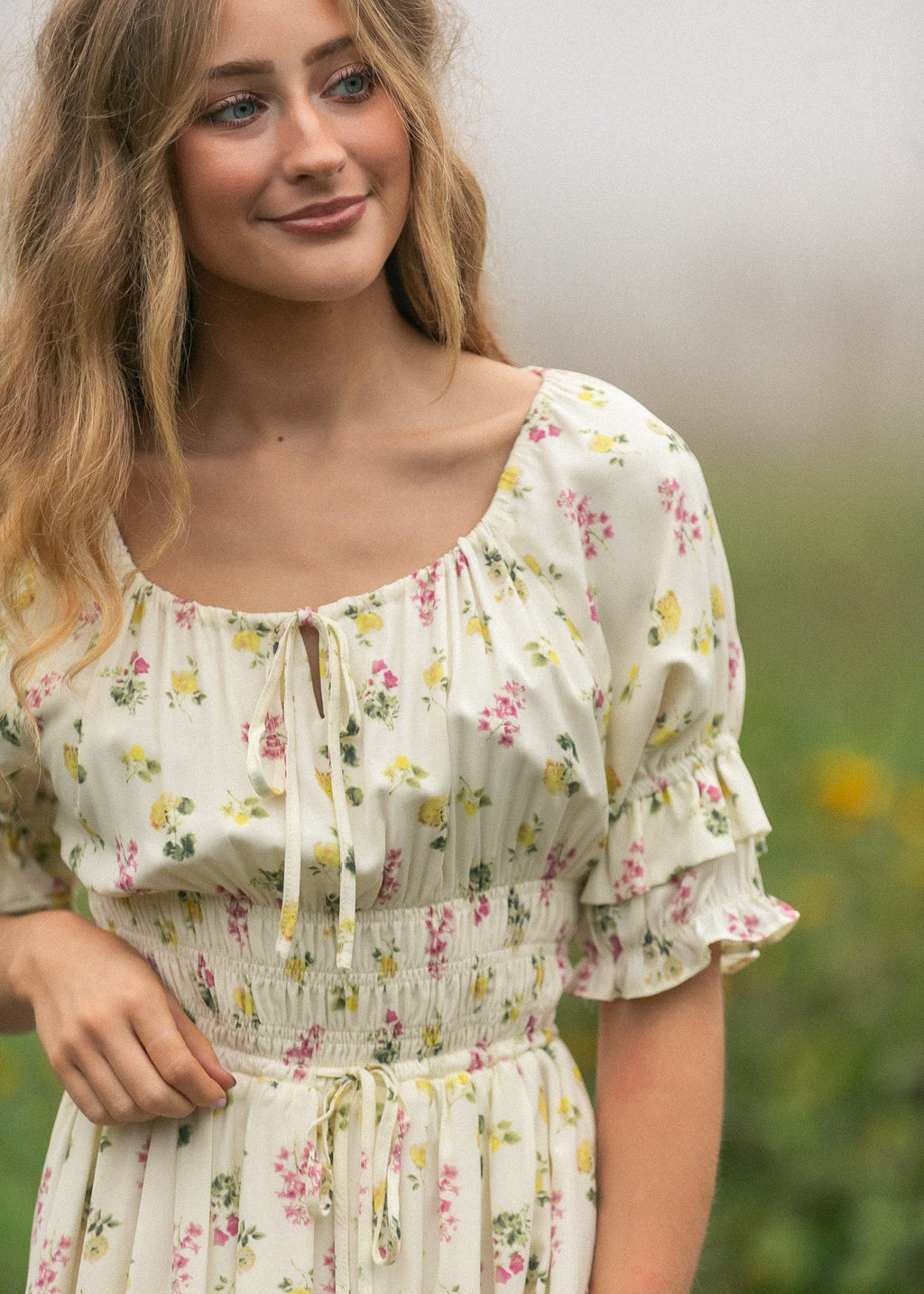 Close-up of cream floral maxi dress with puff sleeves, elastic neckline, and waist tie.