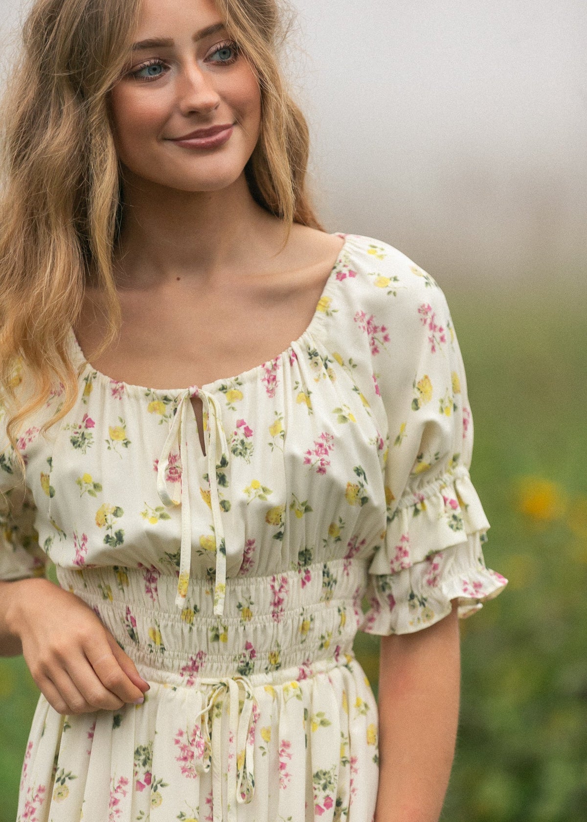 Close-up of cream floral maxi dress with puff sleeves, elastic neckline, and waist tie.