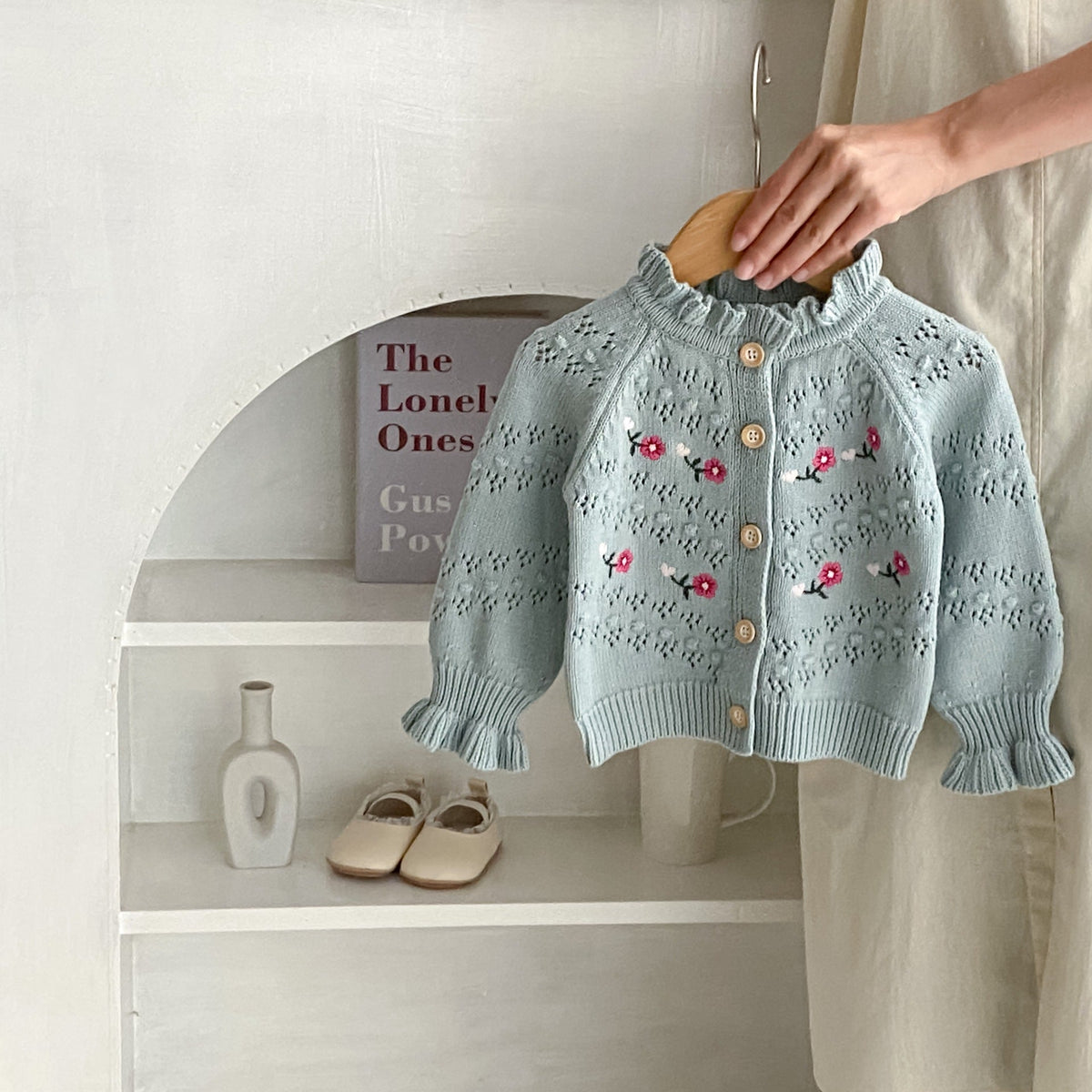 Blue-gray knit cardigan with ruffle neckline, button front, and red floral embroidery.