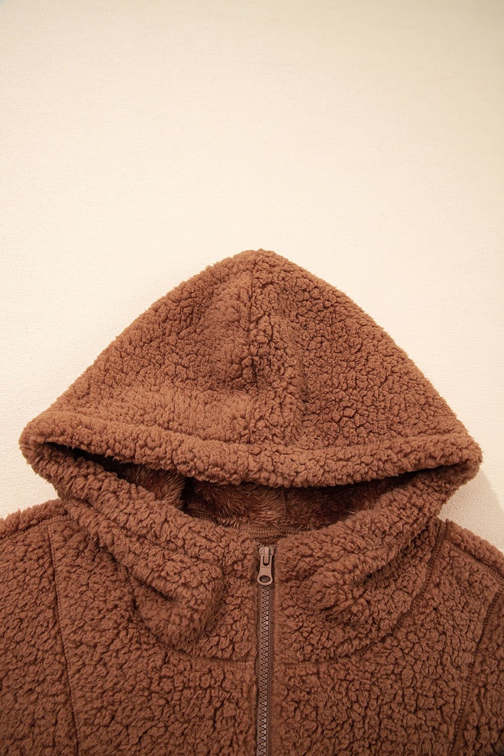 Brown sherpa fleece hood and zipper front of a zip-up hooded jacket