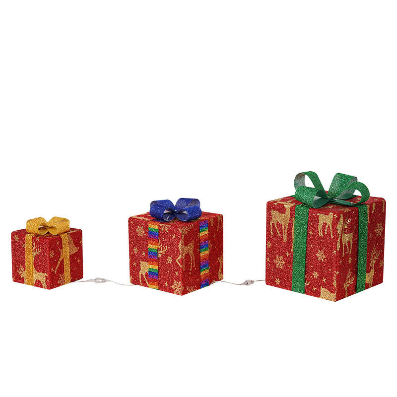 Three illuminated Christmas gift boxes with glitter wrap, ribbon bows, and warm light