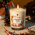 Mystery jewelry candle in clear glass, lit wick, cream cinnamon scent label