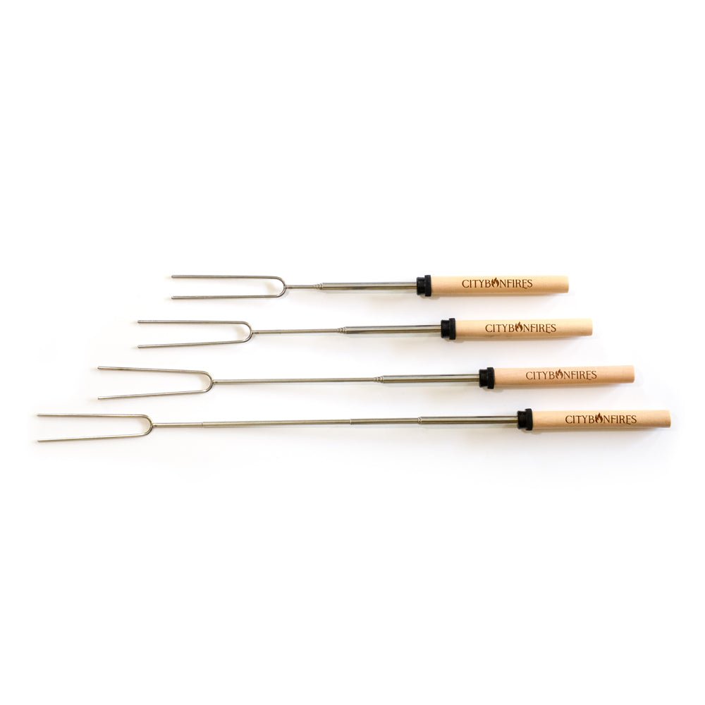 Four s'mores roasting sticks with wooden handles and prongs, laid out