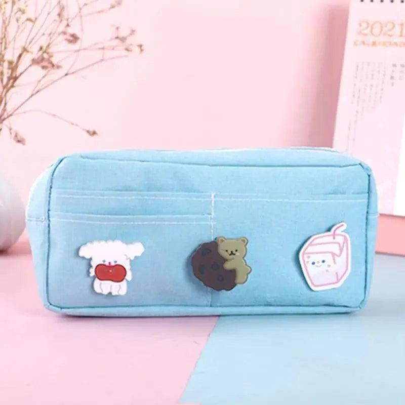 Light blue fabric pencil pouch with cute cartoon patches and zip front, compact shape