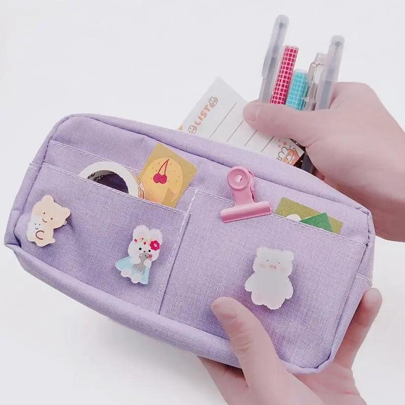 Lavender fabric pencil pouch open with divider pockets and small cartoon appliques