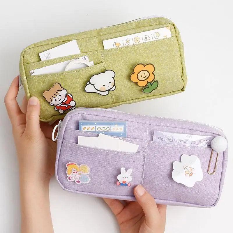 Purple fabric pencil pouch with cartoon patches, zip closure, and rounded handle loop