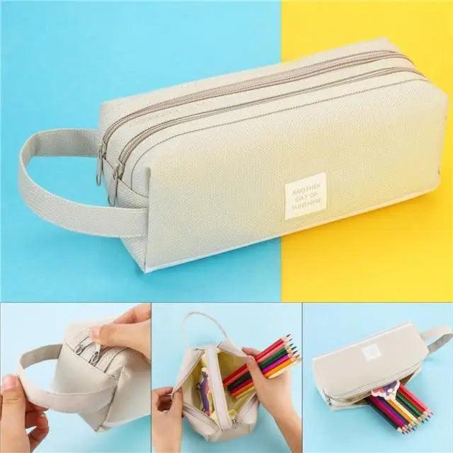 Cream fabric pencil pouch with wrist strap and double zipper, shown with colored pencils inside