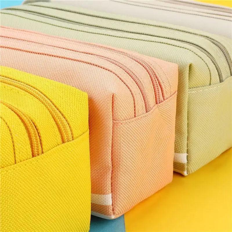 Stacked striped pencil pouches in yellow, peach, and light green with carry straps