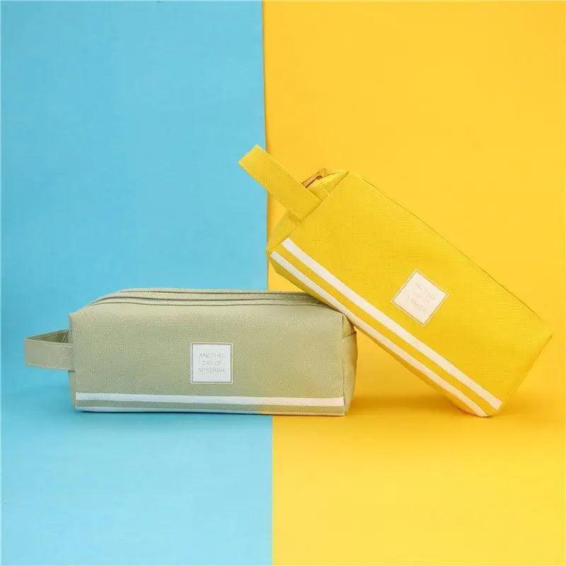 Light gray and yellow striped pencil pouches with carry straps and front label patches