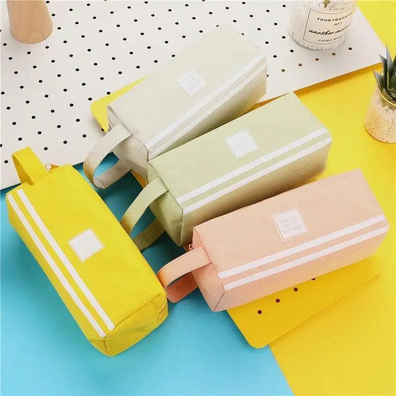 Set of striped pencil pouches in pale gray, yellow, and blush pink with handle straps