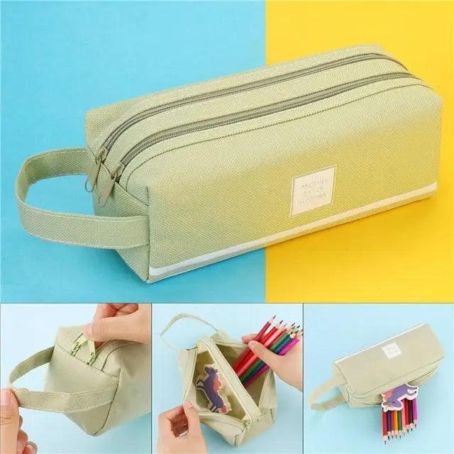 Light gray double-zip pencil pouch with wrist strap and front label badge