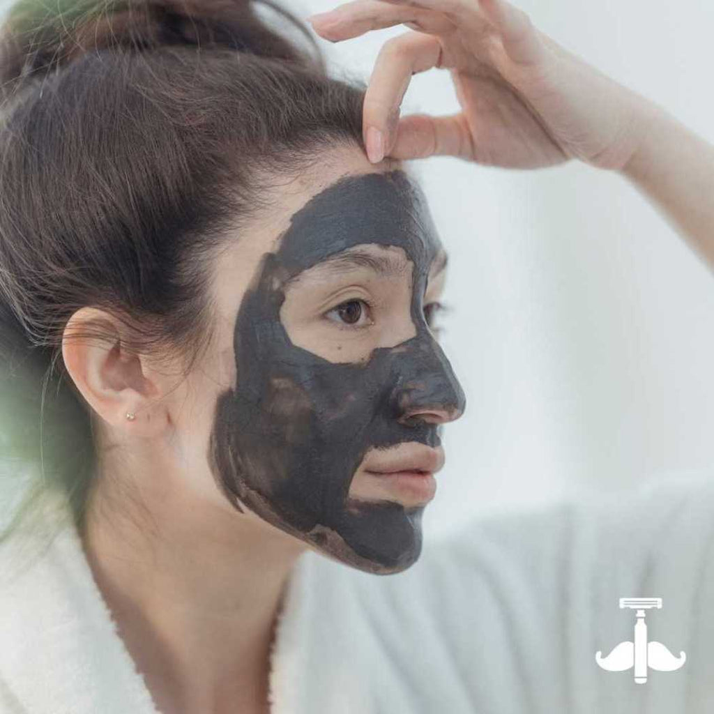 Clay mask stick application: dark charcoal mask on cheek and jawline