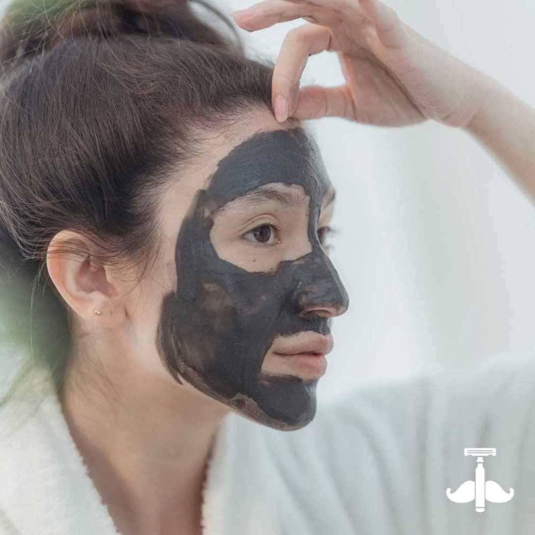 Clay mask stick application: dark charcoal mask on cheek and jawline