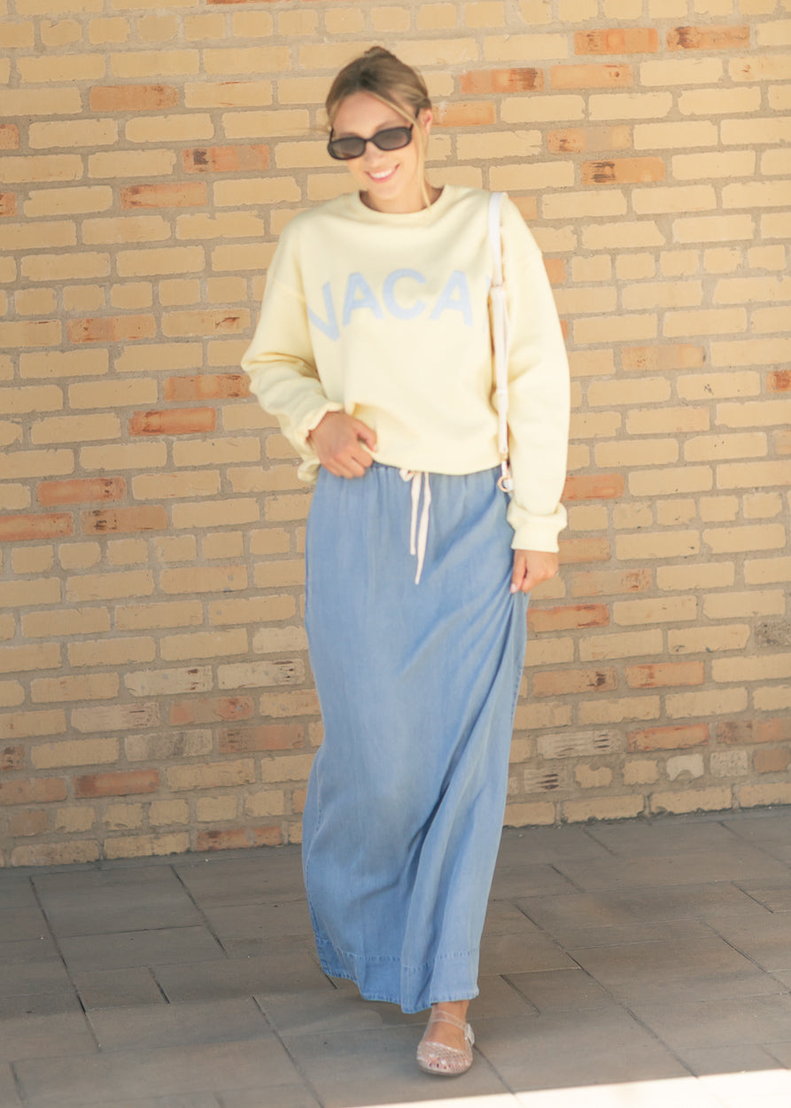 Medium wash chambray maxi skirt with long length, elastic waist, and front slit
