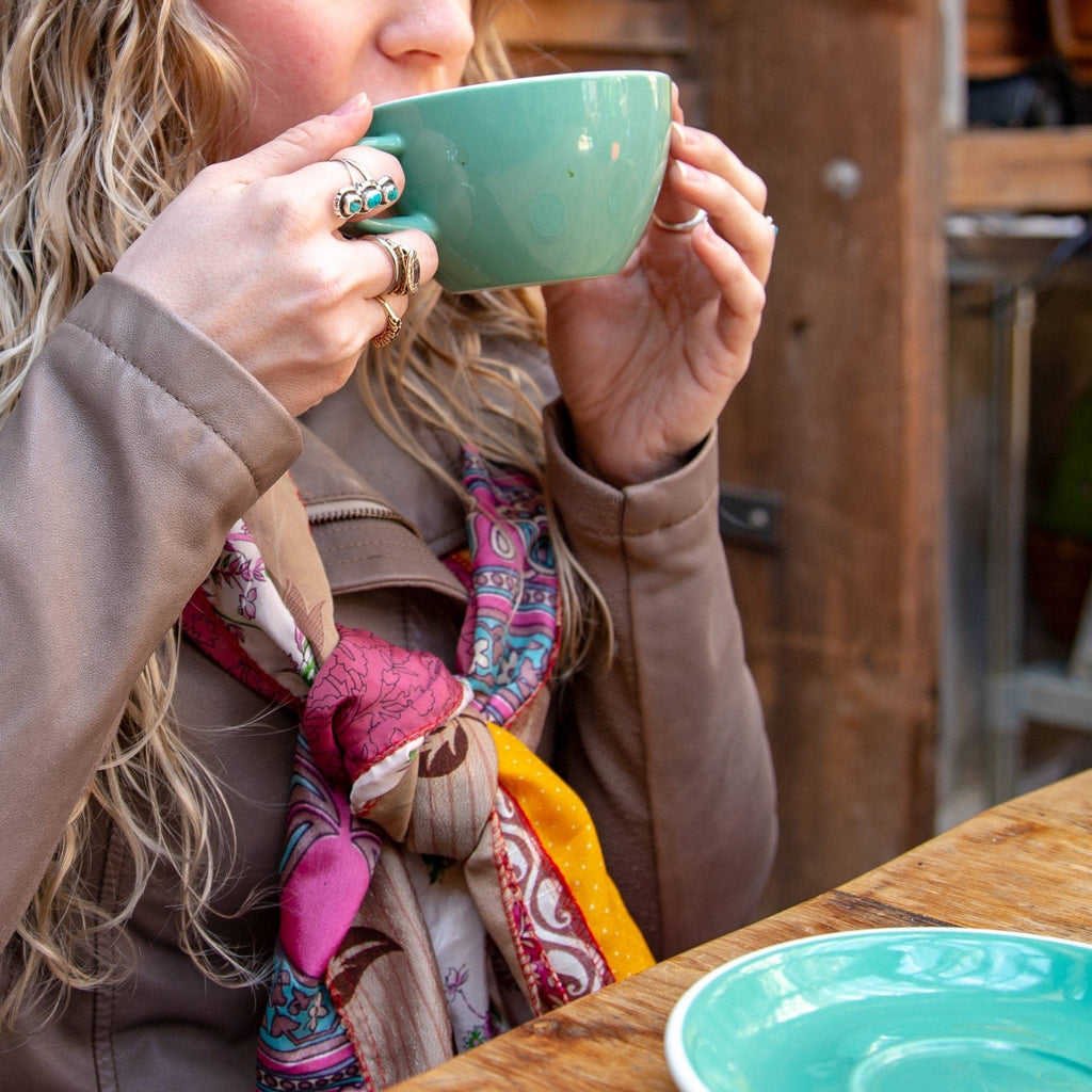 Multicolor printed scarf with pink, teal, and cream details wrapped near the neck