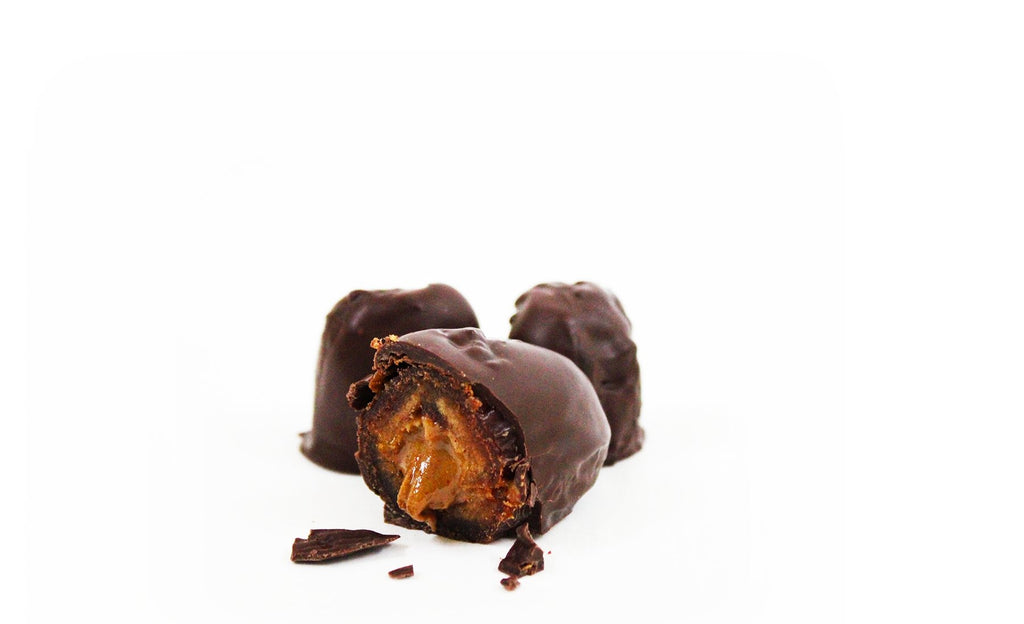 Cut open chocolate-dipped stuffed date with visible filling and chocolate pieces