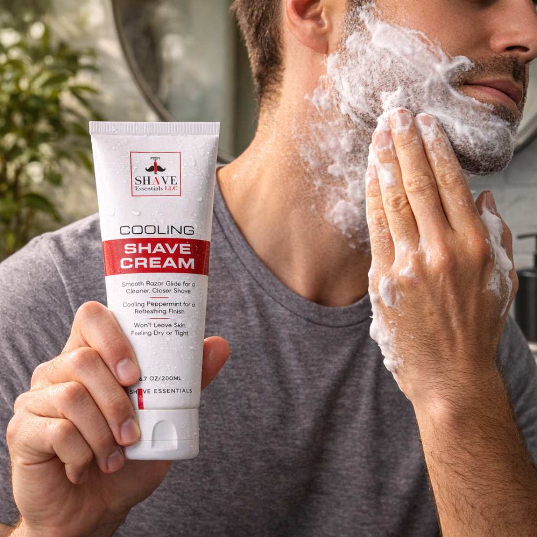 Cooling shave cream tube held while white shaving foam covers man's face
