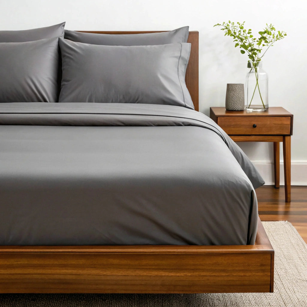 Light gray sheet set with pillowcases and duvet on a wooden bed frame