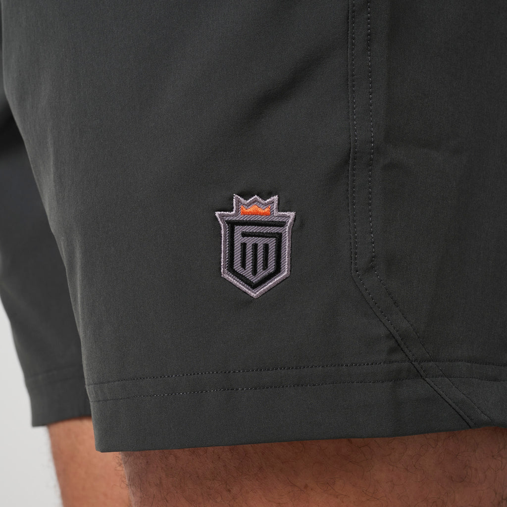 Dark training shorts with embroidered shield logo on the left leg