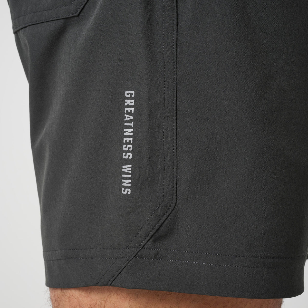 Dark training shorts with vertical text "GREATNESS WINS" on side seam
