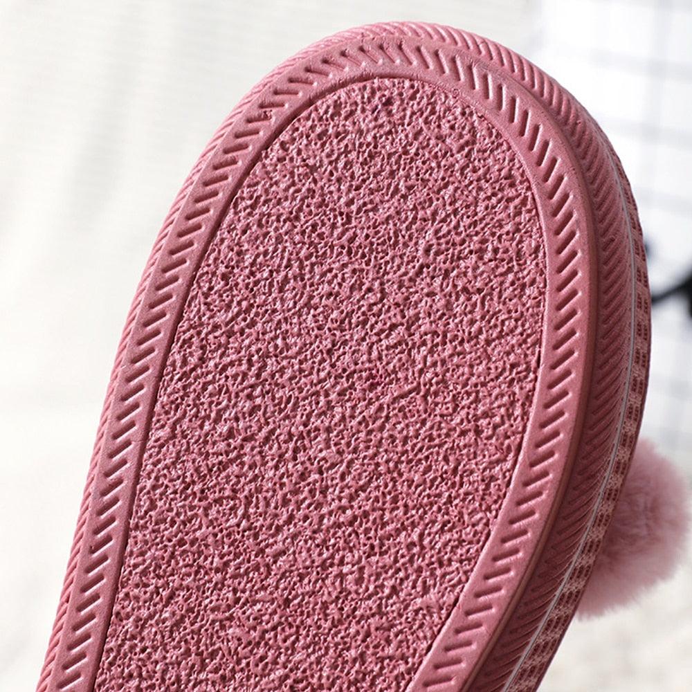 Pink textured rubber outsole of a plush slip-on slipper