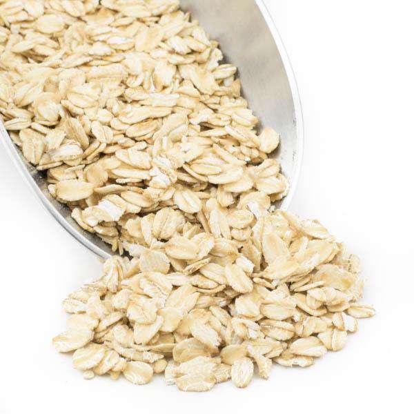 Thick rolled oats in a metal scoop, pale golden flakes