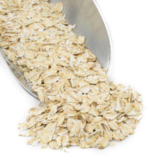 White rolled wheat flakes in a bowl, loose flaky cereal
