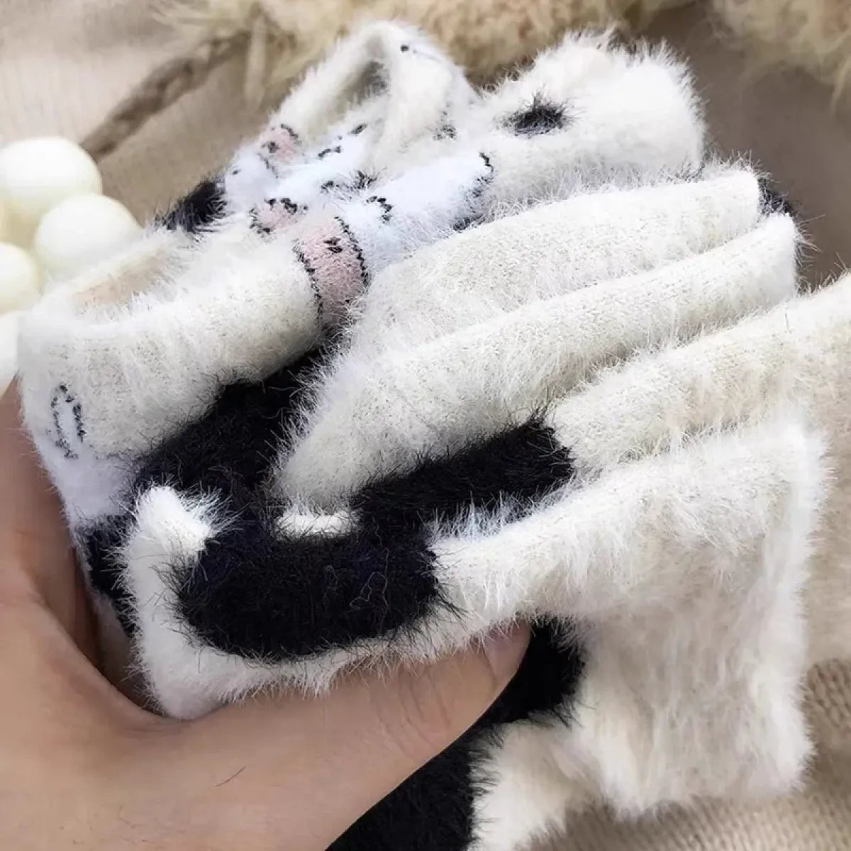 Women’s cow mink velvet socks, plush white with black cow paw accents and soft ribbed cuff