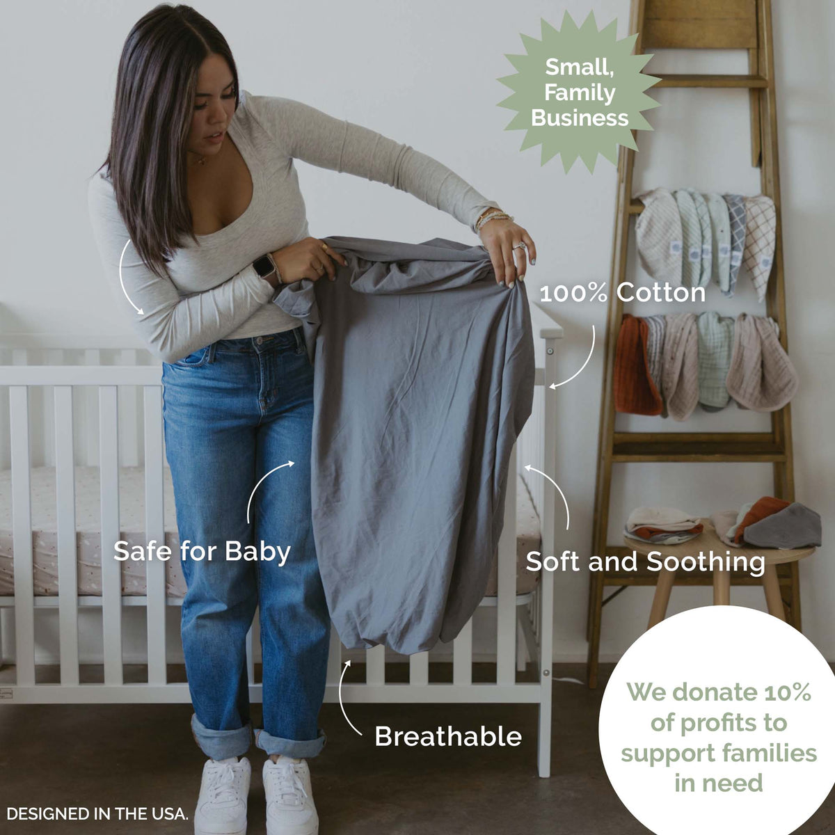 Crib sheet being held; light gray-blue fitted sheet with a smooth, solid surface.